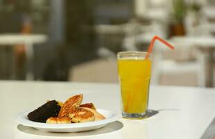 verre de Orange jus avec Plastique paille sur blanc table dans restaurant Extérieur salon zone photo