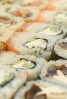 gros plan sur beaucoup de rouleaux de sushi avec différentes garnitures. photo macro de plats japonais classiques cuits. image de fond