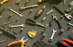 trousse à outils de bricoleur sur une table en bois noire. de nombreuses clés et tournevis, piles et autres outils pour tous types de travaux de réparation ou de construction. outils de réparateur photo