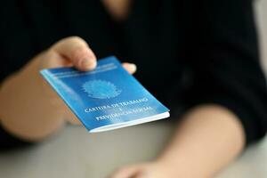 femme patron donne une brésilien travail carte et social Sécurité bleu livre à nous dans emploi Bureau photo