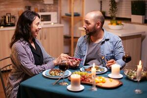 montrant positif grossesse tester à mari pendant romantique dîner. excité couple souriant, étreindre et embrasser chaque autre pour cette génial nouvelles. enceinte, Jeune épouse content pour résultat embrassement homme. photo