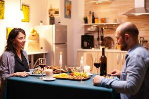 copain et petite amie profiter romantique dîner. parlant content séance à table à manger chambre, profiter le repas à Accueil ayant romantique temps à bougie lumières. photo