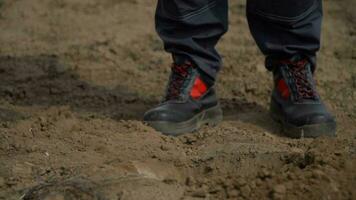 ai généré proche en haut de Humain pieds dans noir des chaussures sur boueux sol photo