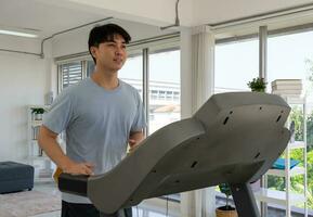 Jeune asiatique homme faire des exercices avec tapis roulant machine à Accueil photo