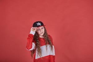 Jeune belle fille mignonne dansant sur fond rouge, adolescente moderne de style hip-hop mince sautant photo