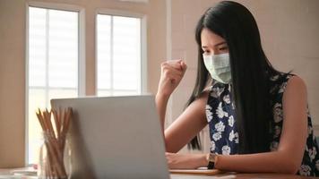 fille portant un masque avec des gestes confiants. elle travaille à la maison pour se protéger contre le virus covid-19.