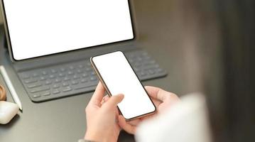 l'image en gros plan de la main d'une femme d'affaires utilise un smartphone à écran blanc avec un ordinateur portable.