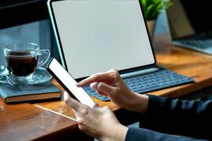 femme d'affaires travaillant sur un smartphone à écran blanc avec une tablette moderne au bureau.