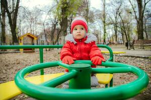 le enfant est filage sur une balançoire dans le terrain de jeux dans le parc photo