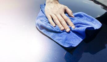 une homme lingettes une voiture avec une microfibre chiffon. voiture polissage. photo