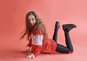 jeune femme urbaine dansant sur fond rouge, adolescente moderne de style hip-hop mince photo