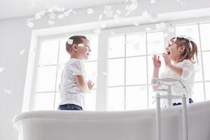 enfant jouant avec des pétales de rose dans la salle de bain à domicile. petite fille et garçon s'amusant et s'amusant ensemble. le concept de l'enfance et la réalisation des rêves, de la fantaisie, de l'imagination photo