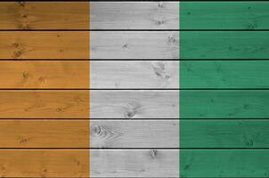 Ivoire côte drapeau représenté dans brillant peindre couleurs sur vieux en bois mur. texturé bannière sur rugueux Contexte photo