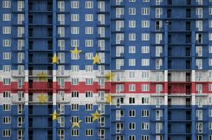 cabo verde drapeau représenté dans peindre couleurs sur à plusieurs étages résidentielle bâtiment en dessous de construction. texturé bannière sur brique mur Contexte photo