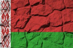 biélorussie drapeau représenté dans peindre couleurs sur vieux pierre mur fermer. texturé bannière sur Roche mur Contexte photo