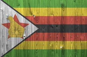 Zimbabwe drapeau représenté dans brillant peindre couleurs sur vieux en bois mur. texturé bannière sur rugueux Contexte photo