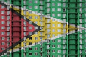 Guyane drapeau représenté dans peindre couleurs sur à plusieurs étages résidentielle bâtiment en dessous de construction. texturé bannière sur brique mur Contexte photo