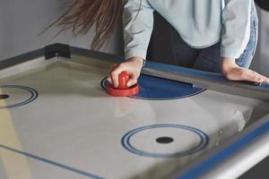 mains de jeunes tenant un attaquant sur une table de hockey sur air dans la salle de jeux photo