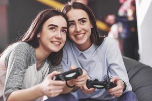 des soeurs jumelles jouent sur la console. les filles tiennent des joysticks dans leurs mains et s'amusent photo