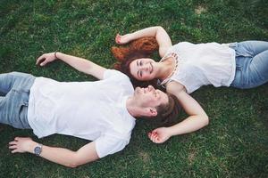 couple romantique de jeunes allongés sur l'herbe dans le parc. Ils ont l'air heureux. vue d'en-haut. photo