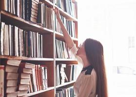 une jeune étudiante cherche le bon livre sur les étagères de l'ancienne bibliothèque universitaire