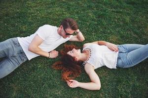 un couple romantique de jeunes allongés sur l'herbe dans le parc. vue de dessus photo