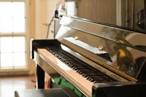 photo recadrée de piano classique dans une pièce avec lumière naturelle à travers une belle fenêtre.