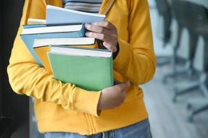 l'étudiante s'est levée et a tenu de nombreux livres dans sa poitrine pour se préparer à l'examen. photo