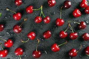 rouge mûr sucré Cerise avec l'eau gouttes sur noir ardoise Contexte. photo