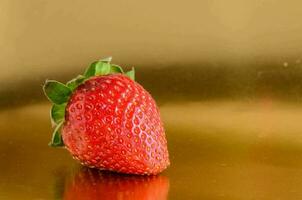 une fraise est séance sur une d'or surface photo