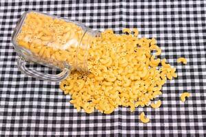 épars non cuit chifferi rigati Pâtes sur noir à carreaux serviette. graisse et mauvais pour la santé aliments. classique sec macaroni. italien culture et cuisine. brut Pâtes photo