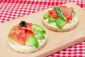 riz gâteau sandwich avec avocat, jambon, Olives et Romarin sur en bois Coupe planche. facile petit déjeuner. rapide et en bonne santé sandwichs. pain croustillant avec savoureux remplissage. en bonne santé diététique casse-croûte photo