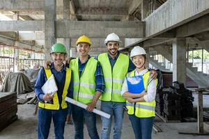 portrait de le la diversité équipe de ingénieur, architecte, ouvrier et sécurité directeur souriant ensemble à le construction site portant sécurité gilet et casque photo