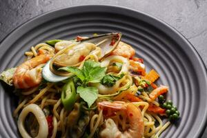 fermer de ivre spaghetti avec Fruit de mer avec crevette, calmar, palourdes, le Chili, et basilic. en bonne santé thaïlandais asiatique nourriture dans une assiette sur une noir Contexte tableau. photo