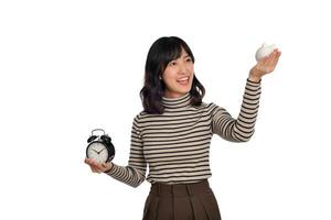 content asiatique femme avec chandail chemise en portant alarme l'horloge et porcin banque isolé sur blanc Contexte photo