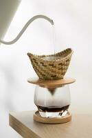 verser chaud l'eau dans le sol café dans une goutteur fabriqué de bambou tisser. photo
