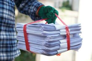 proche en haut homme tenir pile de utilisé papier, lié avec corde. concept, tri des ordures pour recycler suivant pas. éco amical activité. déchets papier gestion. réduire réutilisation, recycler papier. photo