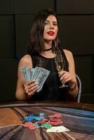 chanceux Jeune brunette avec verre de Champagne et billets de banque séance à poker table photo