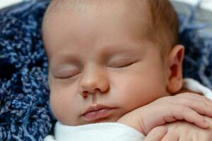 peu bébé garçon en train de dormir dans une panier sur le en bois sol, studio tir. fermer photo