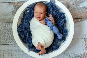 peu bébé garçon dans une panier, Heureusement souriant et à la recherche à caméra, studio coup photo