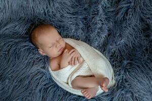 nouveau née bébé garçon dans lit. Nouveau née enfant en train de dormir en dessous de une blanc tricoté couverture. les enfants dormir. photo