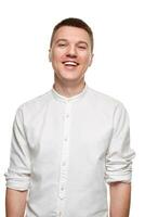 portrait de Jeune homme dans décontractée chemise souriant tandis que permanent contre blanc Contexte photo
