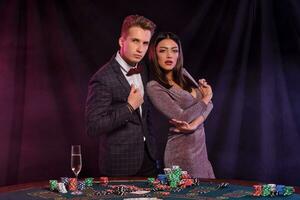 homme et femme en jouant poker à casino, célébrer gagner à table avec piles de puces, argent, cartes, Champagne. noir Contexte. jeu. fermer. photo