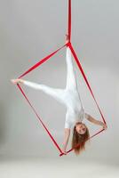 magnifique fille dans une blanc sport costume est performant un acrobatique éléments dans une studio. photo