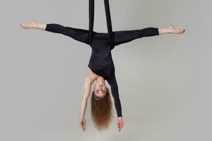 magnifique fille dans une noir sport costume est performant un acrobatique éléments dans une studio. photo