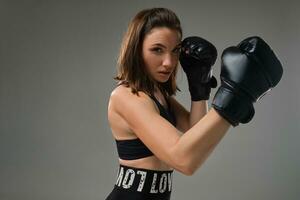 athlétique femme dans boxe gants est pratiquant karaté dans studio. photo