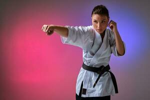 athlétique femme dans traditionnel kimono est pratiquant karaté dans studio. photo