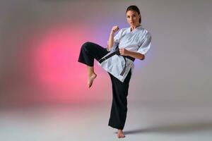 athlétique femme dans traditionnel kimono est pratiquant karaté dans studio. photo