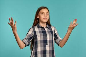 magnifique adolescent fille dans une décontractée à carreaux chemise est posant contre une bleu studio Contexte. photo
