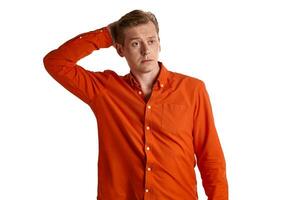 fermer portrait de une gingembre gars dans Orange chemise posant isolé sur blanc Contexte. sincère émotions. photo